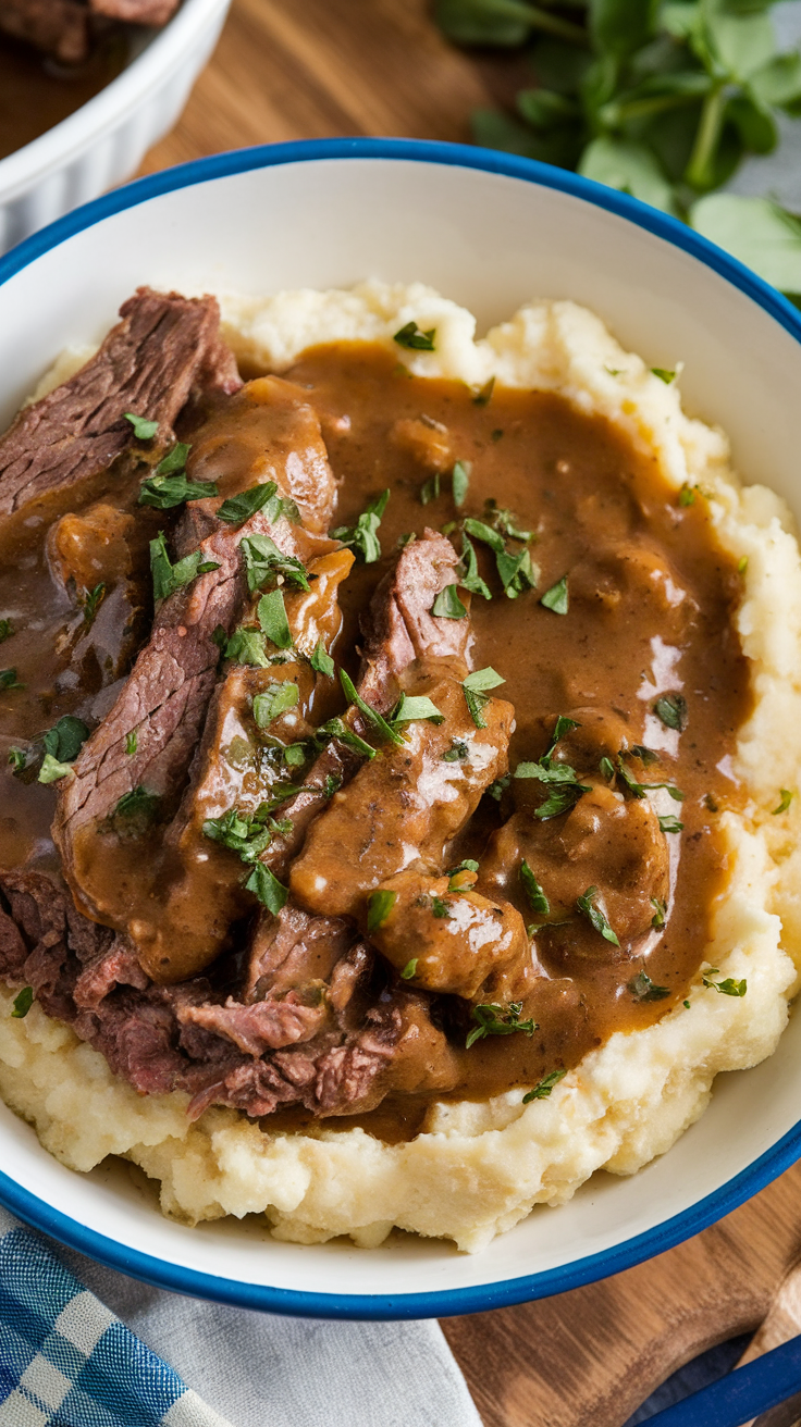 A bowl of beef served with creamy cauliflower mash and gravy, garnished with parsley.